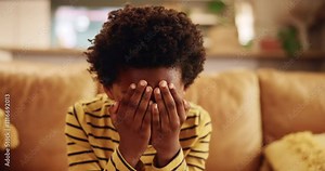 Sad, stress and child with depression, crying and anxiety for mistake in living room. African kid, home and unhappy boy with mental health crisis, lonely orphan or abuse victim with bullying trauma