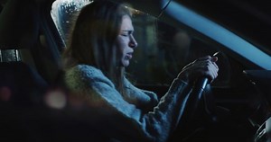 Portrait of an Angry Young Woman Sitting in a Car on a Rainy Night, Screaming. Female Driver Frustrated with Bad News, Getting Emotional, Hitting the Steering Wheel, After a Conflict with her Partner