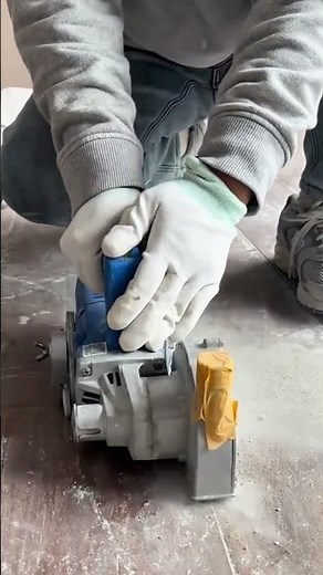Worker using wall chaser machine to cut precise grooves in concrete floor for electrical conduit