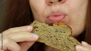 A woman bites of whole grain bread. Close-up portrait. Woman's mouth eating crusty bread