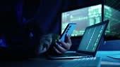 Cyber crime. Laptop screen and silhouetted hoodie man