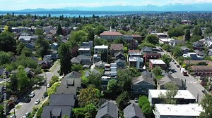 Drone flying low over upper Queen Anne with Olympic mountains and the Puget sound in the backgrounds. Clear summer day over an iiconic Seattle neighborhood.