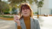 Middle age woman business executive smoking cigarette at park