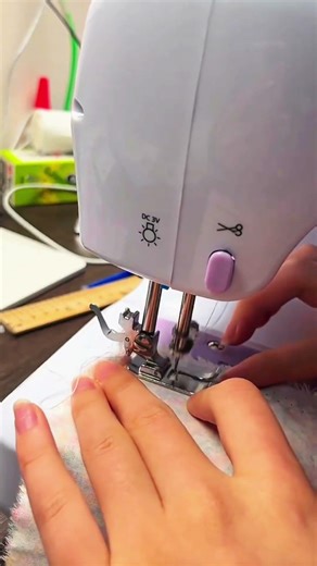 Compact sewing machine stitches fabric under guided hands with low-voltage light