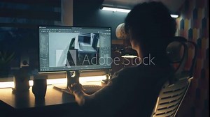 Male 3D designer working on 3D modeling project of house and making exterior in professional computer program, using pc while sitting at the table at home in the evening.