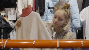 Young teenager girl looking jacket in clothes showroom at shopping. Young woman choosing clothes in fashion boutique. Girl teenager shopping in clothes store