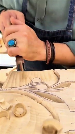 Detailed hand carving of intricate floral patterns on a smooth wood surface