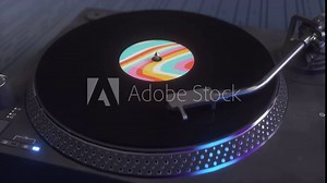 Vinyl record is being played on a turntable. Closeup of a vinyl record slowly rotating on a dark background