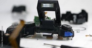 Closeup of disassembled camera spare parts in detail on the desk in workshop. Broken camera for service repairs. Panning shot.