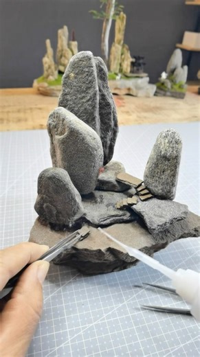 Art Viral 🎨 on Instagram: "Golden Stone Landscape Art is a Chinese miniature artist who builds detailed landscapes using stones, moss-like greenery and natural textures. He carefully places each rock to shape mountains and terrain, then adds adhesive and fine green materials that resemble grass and vegetation, slowly bringing the scene to life. Artist: mj15006597 / 金石造景 on Douyin #art #artist #miniature"