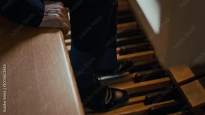 Tilt down view of legs of unknown musician wearing black shoes pressing pedal keys and swell pedals of organ while playing composition