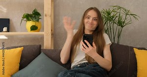 Woman reads the news on Internet and is indignant. Annoyed angry girl looking smartphone at home indoors. Asks what is it