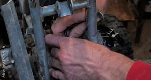 In the garage, a man is repairing his child's ATV by replacing a broken part. Repairing an ATV with your own hands in the garage and replacing broken parts. ATV repair concept.