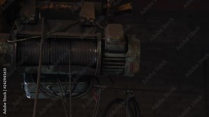 old hoist with rotating roller pays out metal cable and moves aside in powerful production plant