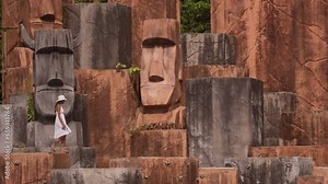 Woman Walking On Stone Pedestals Near Head Statues