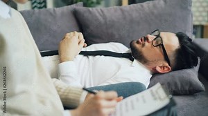 Close up of psychologist writing and male patient answering questions in office passing psychological test for diagnosis. People and psychology concept.