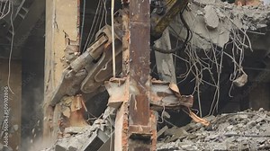 Close up video of a construction excavator destroying the remainings of the building. Camera showing the demolition of the beams inside the building with concrete and trash around.