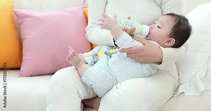 Mother feeding formula to her baby from a bottle
