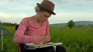 female artist paiting a jungle themed picture with watercolours, outdoors in a nature Stock Video