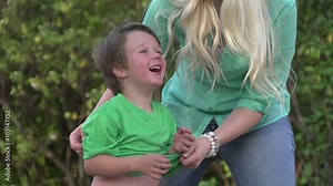 Slow motion of mother taking off shirt over childs head with child laughing