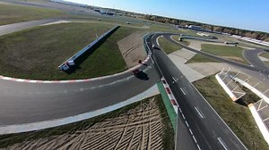 aerial filming of a circuit race on an asphalt circuit, fpv drone, racing cars go fast, time trials, sharp turns