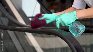 Staff cleaning the escalator handrail in department store to prevent and kill germs the spread of pandemic Covid-19 and Coronavirus, healthcare and hygiene concept