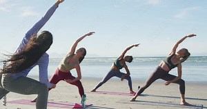 Group of diverse female friends practicing yoga at the beach