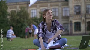Hysterical young woman crumpling and throwing paper. Sitting with notebook computer and textbooks outdoors. Slowmotion. Stock Video
