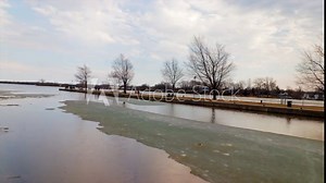 Time lapse of a canal on Saint Lawrence River in Montreal, Quebec, Canada, also showing a pathway and pedestrians passing by during pre-spring season.