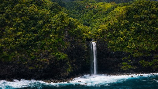 Cliffside waterfall above blue waves