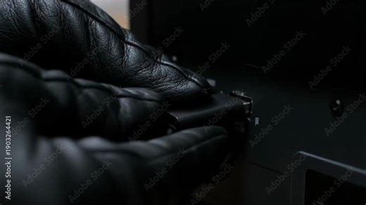 Gloved hand inserting a USB flash drive into a computer port. Cyber security or data theft concept