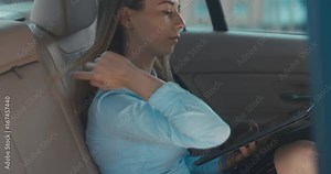 Attractive elegant business lady executive rides in a car with brown leather seats, using her portable tablet computer. 4K UHD RAW edited footage