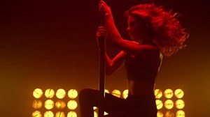 Erotical pole dancer making sensual performance in nightclub. Fit lady poledance performer moving body seductive in spotlight. Hot girl dancing sexually holding pylon at strip club. Striptease concept