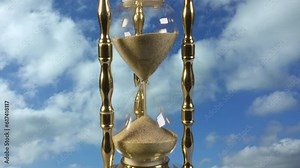 Time flies backwards into the past. Track up to a timelapse hourglass going backwards back in time with a timelapse sky and clouds in the background,
