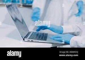 scientist using laptop with sample of liquid