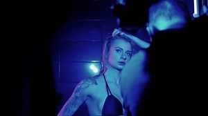 Sexy photo model takes a shower in a swimsuit, poses in front of a switch. Monochrome lighting, blue color.
