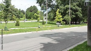 side street road in foreground with ascending descending street road in background separated by island with trees on other side with car vehicle passing, wide shot