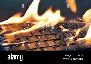 Burning keyboard. Keyboard is engulfed in flames on a desk.Close up of a burning keyboard on fire. Overheated Technology Concept