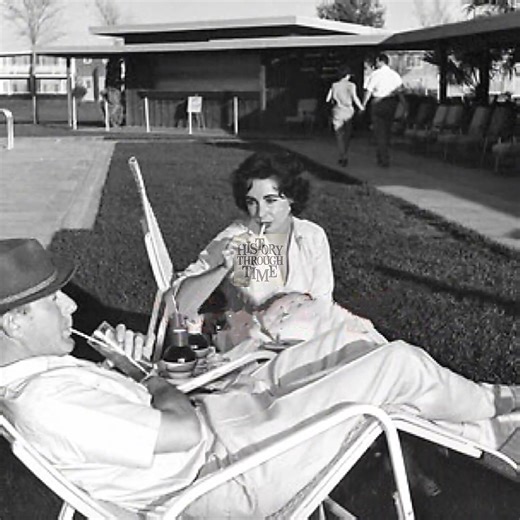 "Elizabeth Taylor and her second husband, Michael Wilding, are photographed by the pool at the Sahara Hotel in Las Vegas, 1956, capturing a moment of leisure and elegance during their high-profile marriage. By this time, the couple had been married for four years, having tied the knot on February 21, 1952, in a quiet ceremony in London. Wilding, a refined British actor, was nearly 20 years her senior, and their relationship was often noted for its gentleness and shared love of privacy amid growi