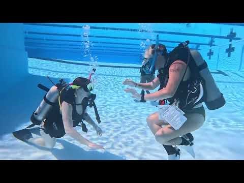 Two Women Scuba Diving Playing Rock Paper Scissors.