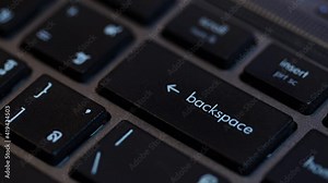 Human fingers press the Backspace key on the computer keyboard.