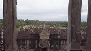 Inside Angkor Wat entrance gate framed with columns. Park with lush nature surround the main temple. Siem Reap, Cambodia