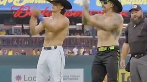 Two shirtless men dance at baseball game