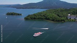 Lake Akan, Japan: Aerial drone footage of a cruise boat sailing on the lake Akan with the Mount Oakan volcano in the backround in the Akan-Mashu National Park in Hokkaido in summer in Japan.