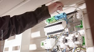 Electrician placing loose wires in electric panelboard before connecting them
