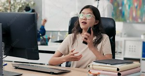 A young beautiful girl is waiting at work for important phone call, sitting in front of computer, receiving a call on smartphone, good news, awaited information, winning a contest, victory a bid
