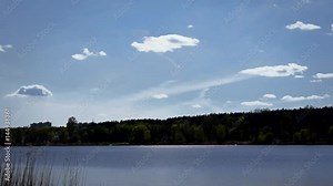 Scenic time lapse with beautiful white cumulus clouds moving over lake or river. The clouds are bubbling, boiling and dissoving in the air.