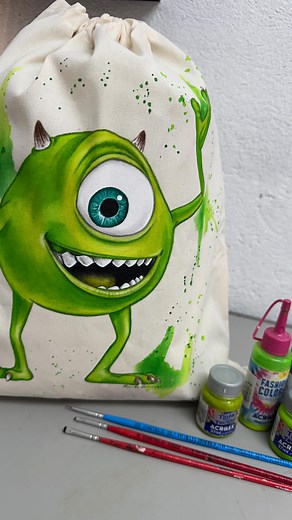 A mochila de algodão cru da Shirley ganhou uma customização com o Zóiudinho da mamãe 👁️💚 Feita à mão com tintas de tecido @acrilex_oficial e pincéis @pinceis_castelo ✨ 👉 E aí, o que vocês acharam? Quem aí também é fã desse Zóiudinho da mamãe? 😍💚 #PinturaEmTecido #Customização #PriscilaCamargoArts #mikewazowski #customizacao #custom #customized #pinceiscastelo #acrilex #fabricpainting | Priscila Camargo Art's