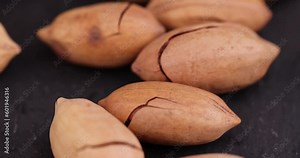 cracked unpeeled pecans close-up on the table, a pile of pecans in the shell