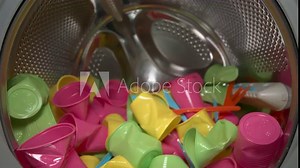 Inside view of the washing machine drum with colored food plastic, close-up of the drum during the spin cycle. Concept of recycling plastic and ecology. Plastic waste.